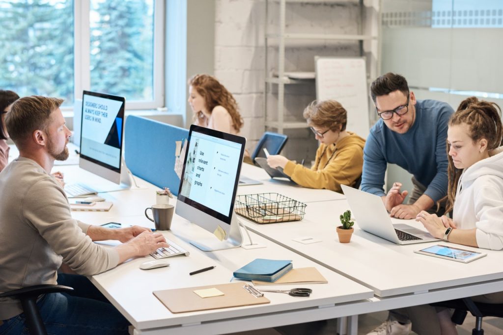 a group of people sitting around a table with computers