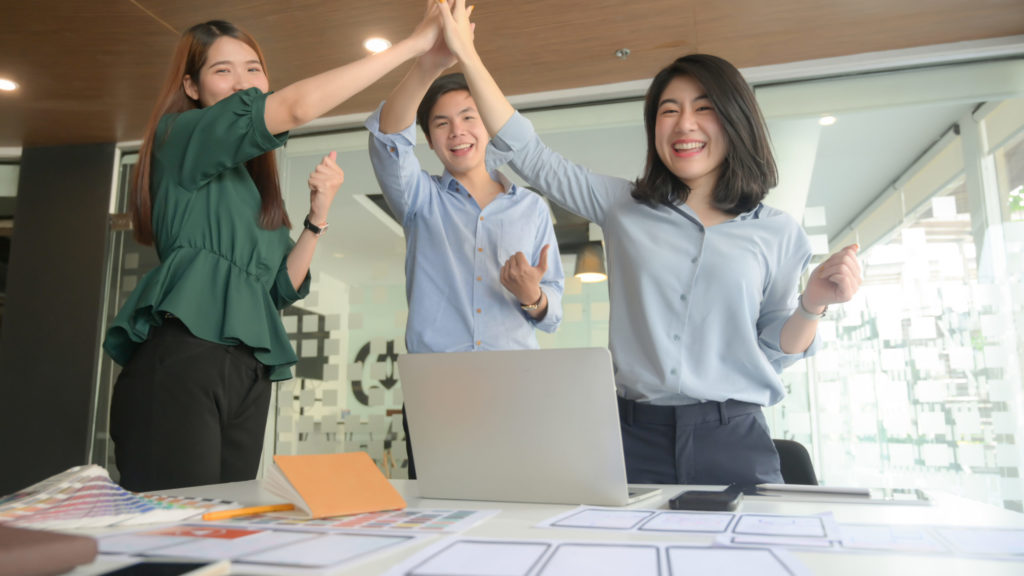 a person raising the hands in the air in front of a laptop