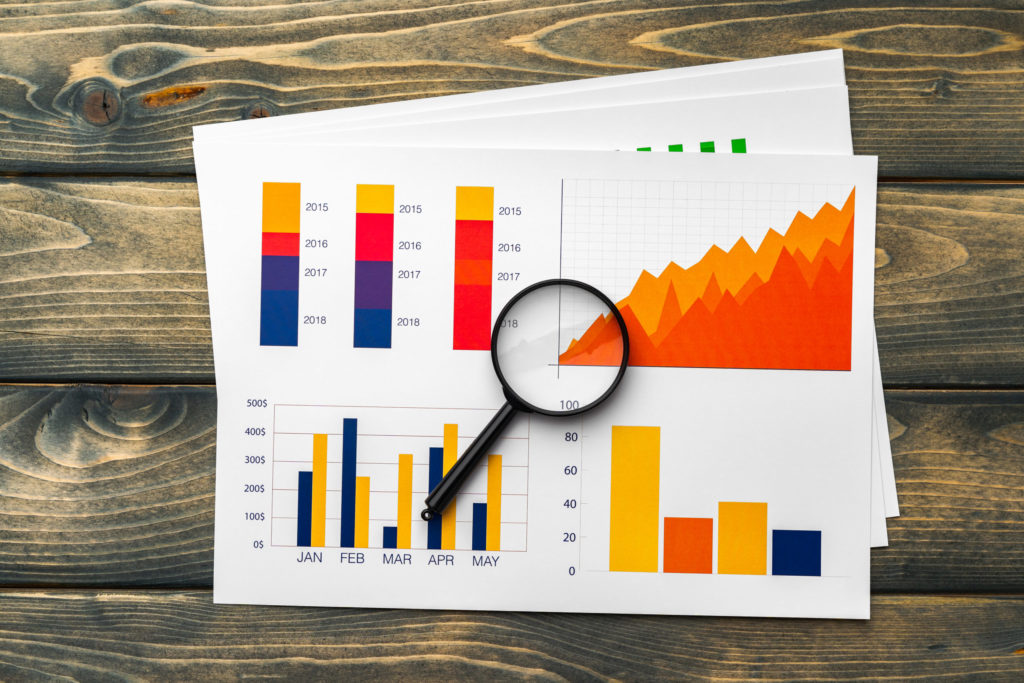 Business graphs and magnifying glass on table