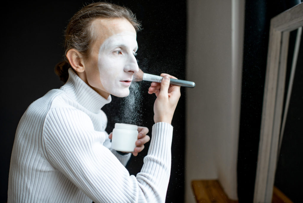 Actor applying makeup on his face