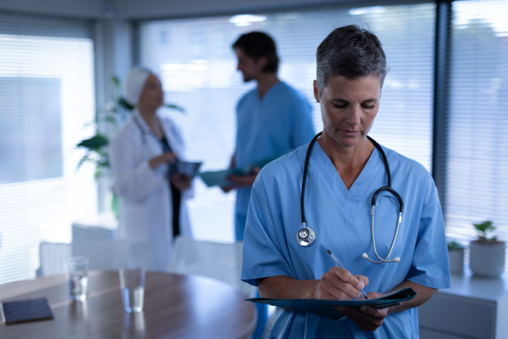 Female surgeon writing in medical report in clinic at hospital