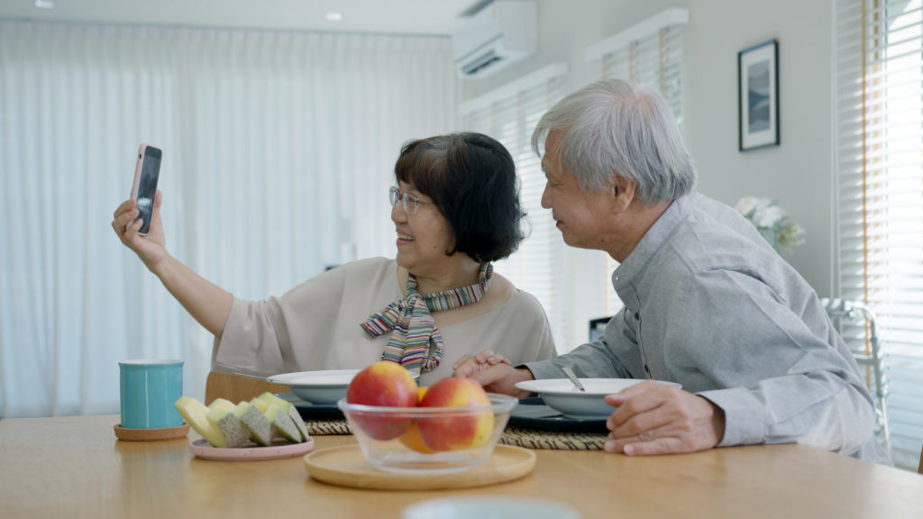 Young senior asia citizen couple hold mobile phone selfie videocall online