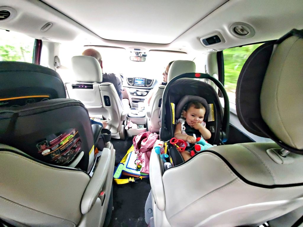 A panoramic view of the inside of a minivan filled with a baby in a car seat